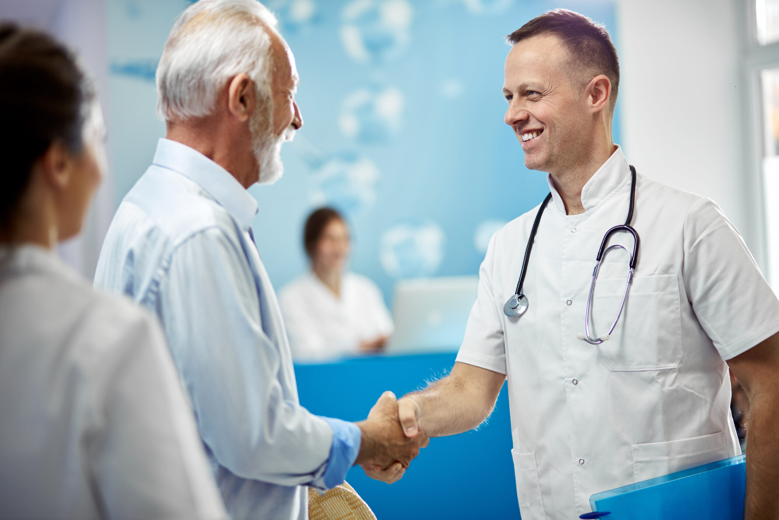 Happy doctor handshaking with senior patient at the hospital.