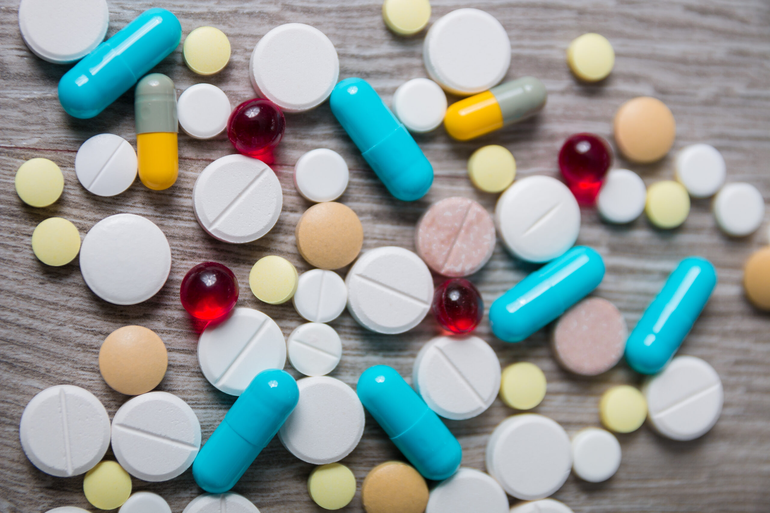 lot of colorful medication and pills from above on grey wooden background. Copy space. Top view, frame. Painkillers, tablets, generic , drugs.