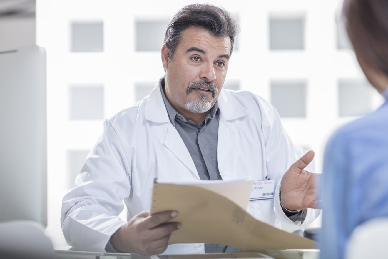 Male and female doctor sitting at table, having conversation