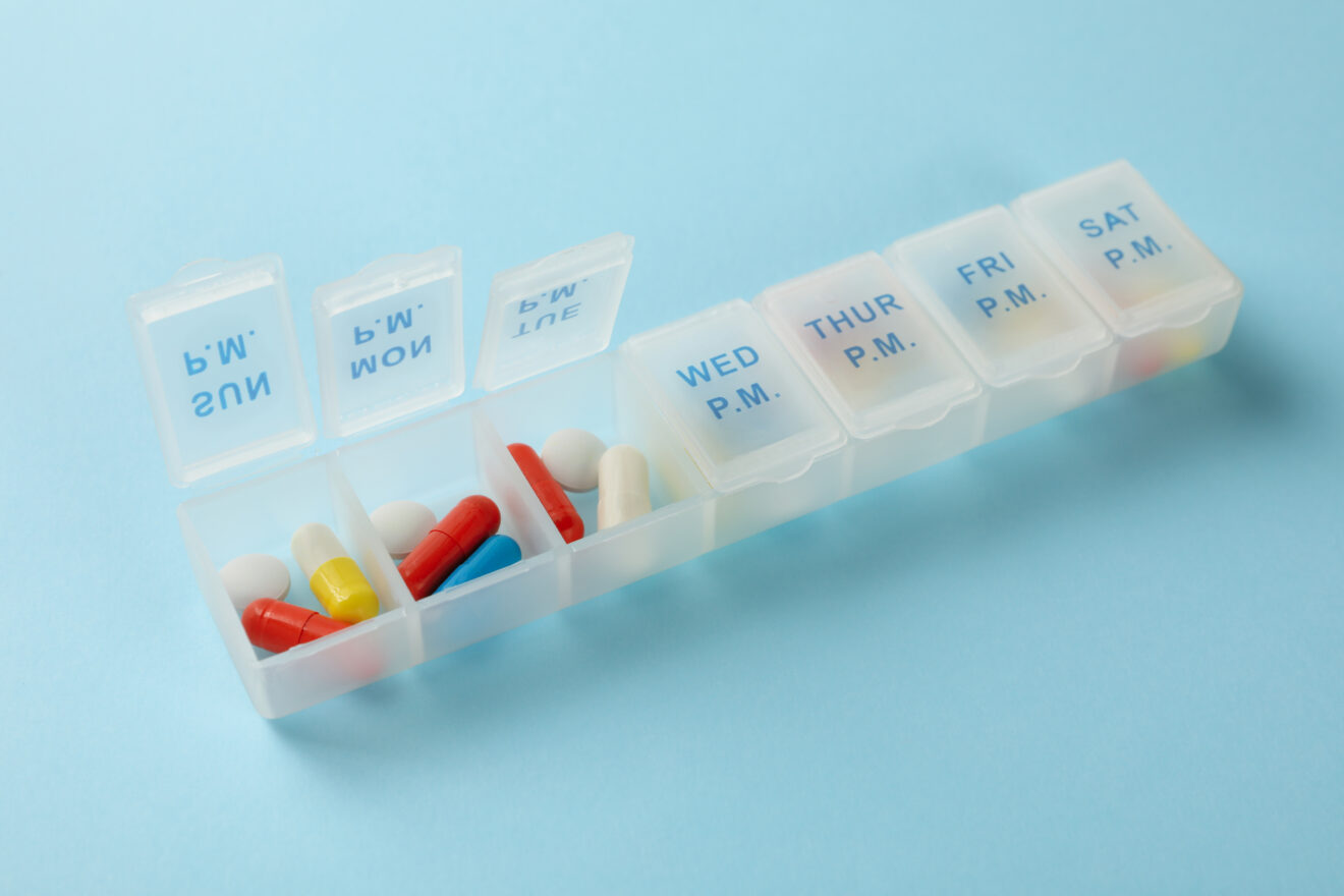 Plastic containers with pills on blue background